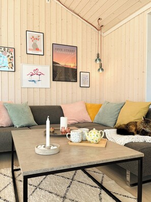Ein gemütliches Wohnzimmer mit Holzwand, einer Couch, einem Couchtisch und einer Katze.