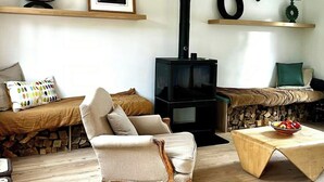 Ein gemütliches Wohnzimmer mit einem Vintage-Sessel, einem Holztisch, einem Kamin und einem Fernseher.