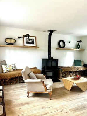 A cozy living room with a vintage armchair, a wooden coffee table, a fireplace, and a television. - Charming house in Lyons-la-Forêt (Lyons-la-Forêt)