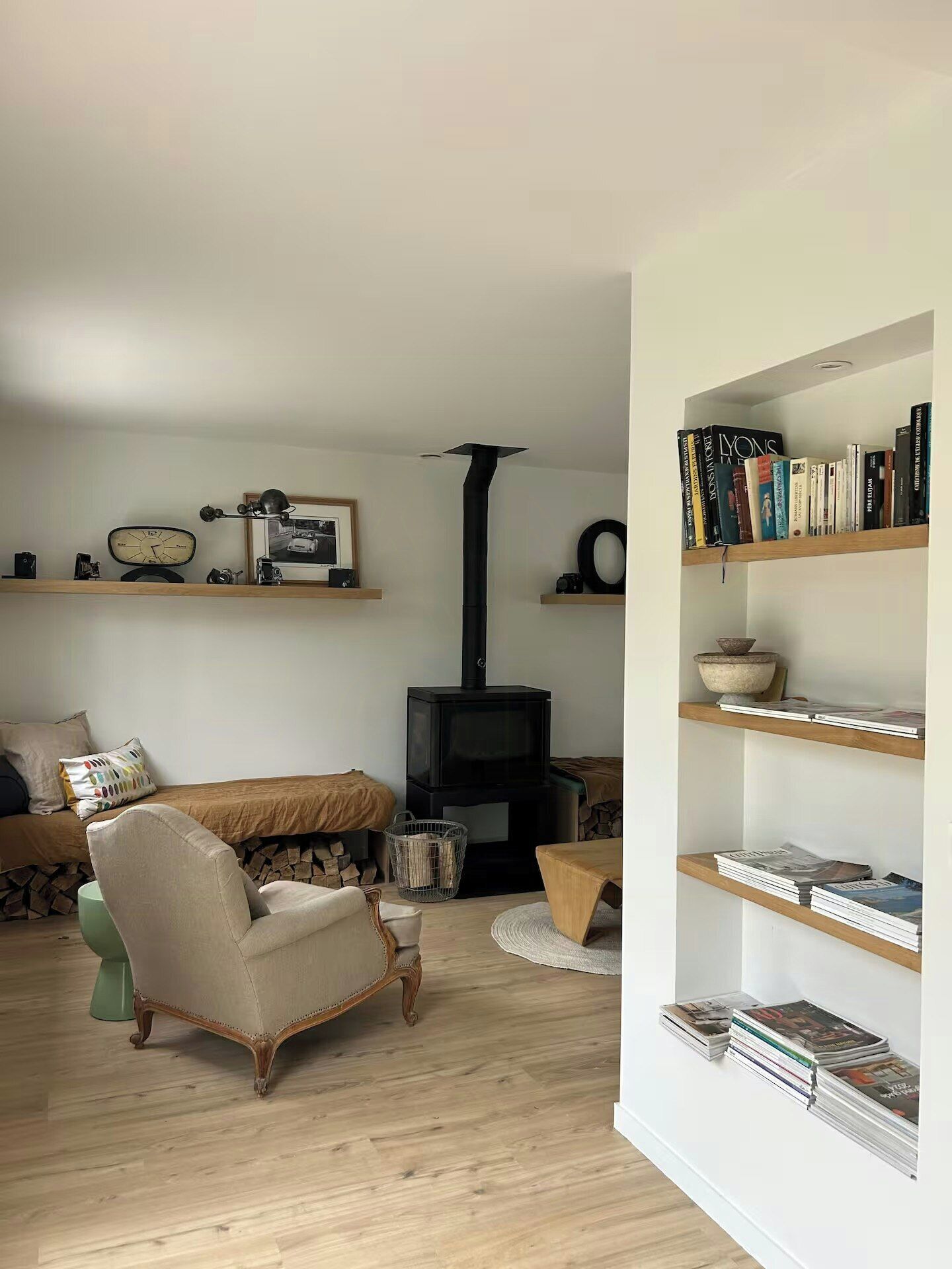 A living room with a fireplace, bookshelves, a sofa, and a vintage armchair.