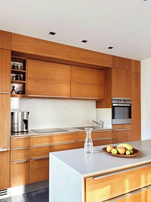 A modern kitchen with wooden cabinets, stainless steel appliances, and a central island with a bowl of fruit. - House with private jetty on Neversdorfer See (Leezen)