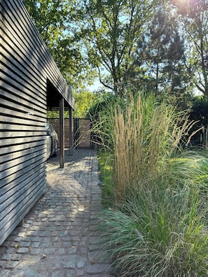 A cobblestone path leading to a wooden building with a car parked outside. - House with private jetty on Neversdorfer See (Leezen)