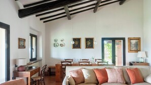 A living room with a sofa, dining table, chairs, and a kitchen area. - Traditional Tuscan villa on hill with pool (Magliano in Toscana)