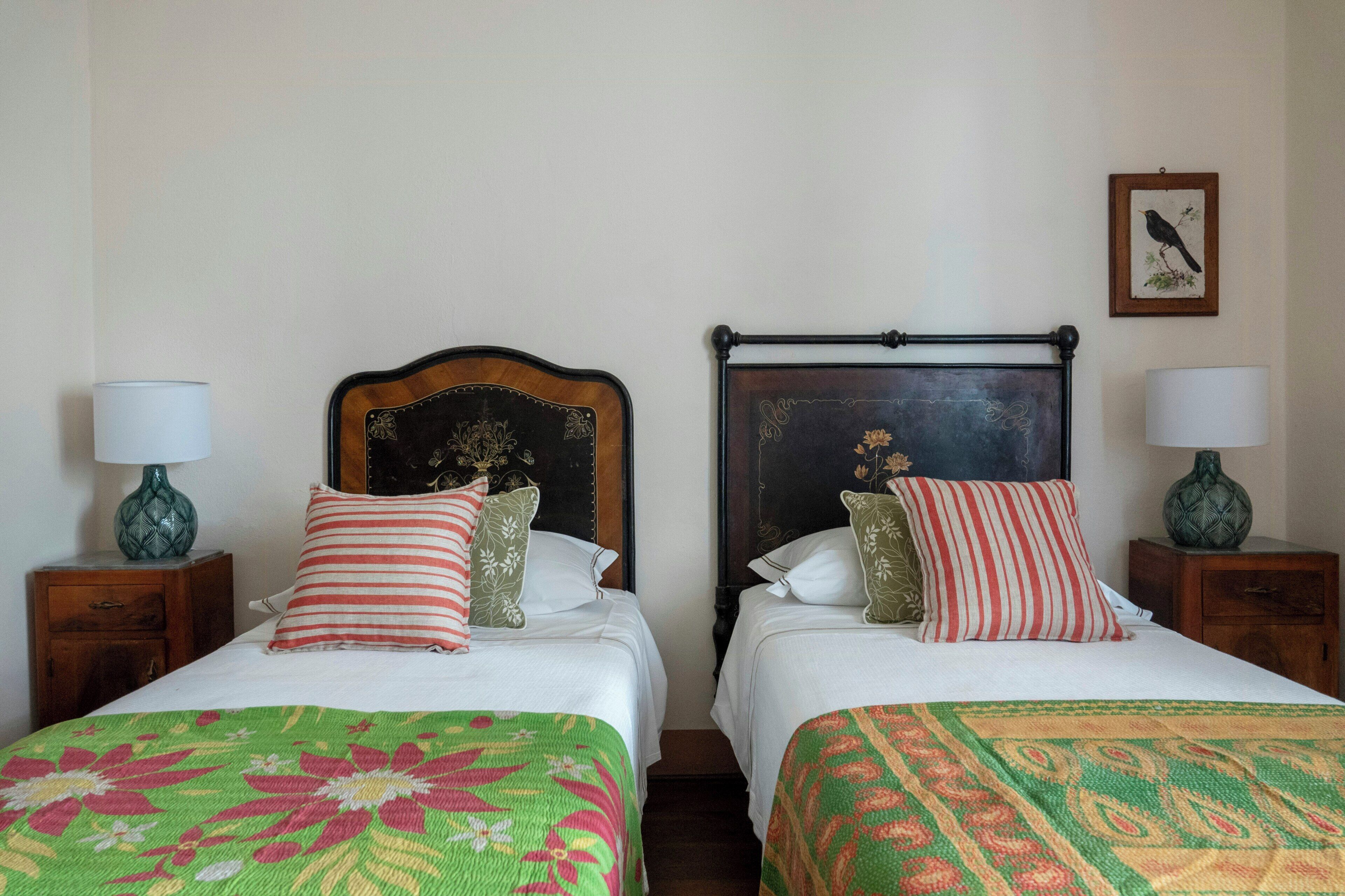 Deux lits simples avec des têtes de lit, du linge de lit blanc et des coussins décoratifs.