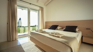 Ein modernes Schlafzimmer mit einem großen Bett, einem Nachttisch und Blick durch die Glastür.