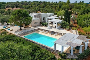 Eine moderne Villa mit Swimmingpool, Sitzgelegenheit im Freien und einem Garten.