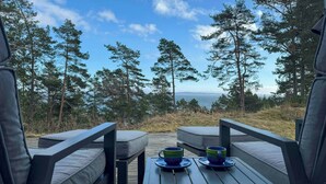 Terraza con dos sillas y una mesa, con vista a un bosque y un paisaje lejano.