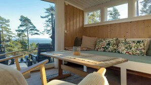 Una cabaña de madera con una mesa de comedor, sillas y un sofá con cojines estampados.