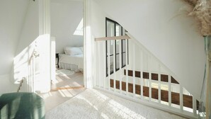 Quarto com cama, janela e escada.