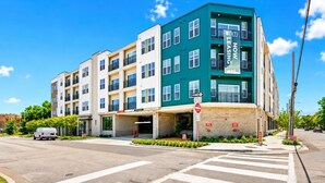 A multi-story building with a green and beige facade, a 'Leasing Now' sign, and a 'One Way' street sign. - Bishop Arts Getaway | Yoga, Gym & Entertainment (Dallas)