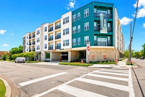 A multi-story building with a green and beige facade, a 'Leasing Now' sign, and a 'One Way' street sign. - Bishop Arts Getaway | Yoga, Gym & Entertainment (Dallas)