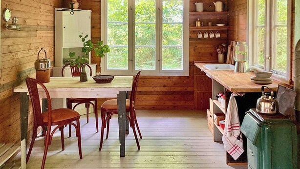 A wooden cabin interior with a dining table, chairs, a sink, and a stove. - Off-grid cabin in your private Swedish forest (Simlångsdalen)