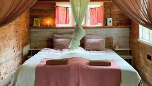 A cozy bedroom with a bed, pillows, a canopy, and a window with curtains. - Off-grid cabin in your private Swedish forest (Simlångsdalen)