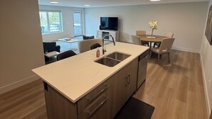 Una cocina moderna con una isla central, un comedor con mesa y sillas, y un televisor montado en la pared.