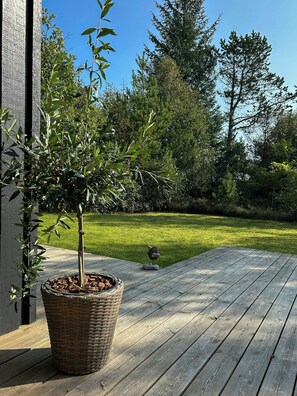 Eine Holzterrasse mit einem Blumentopf und einer Vogelstatue.
