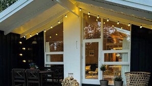 A wooden deck with a bench, chairs, and a table. There are string lights and potted plants. - Holiday home by Ålbæk Beach for the whole family (Ålbæk)