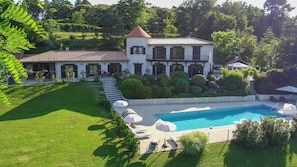 Ein großes Haus mit Swimmingpool, Garten und einer Treppe zum Eingang.