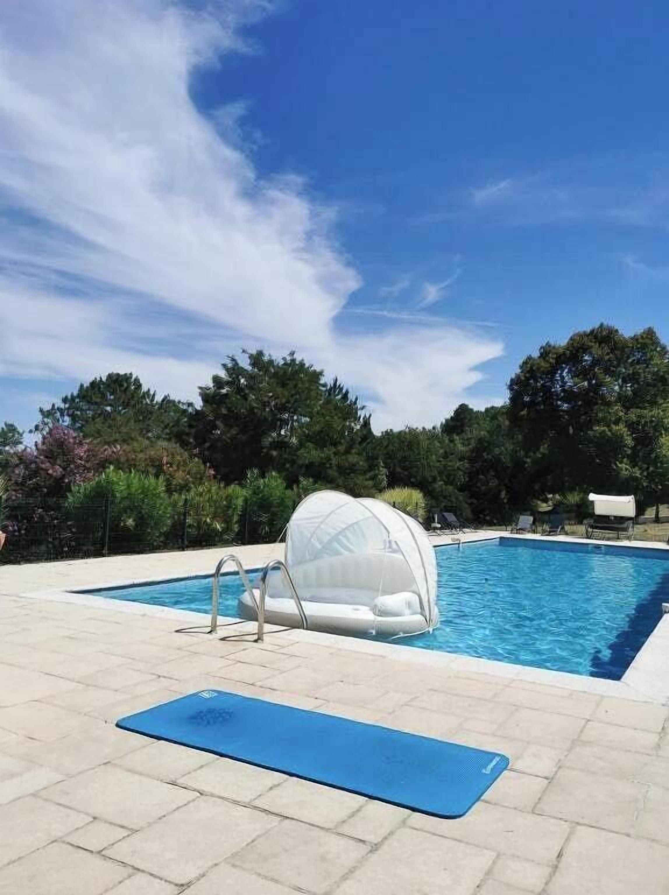 Ein Schwimmbecken mit einer schwimmenden Konstruktion, einer blauen Matte und blauem Himmel.