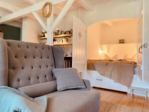 Ein gemütliches Zimmer mit einem großen, gepolsterten Sofa, einer kleinen Bank und einem Bett mit Kopfteil.