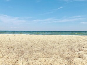 Ein Strand mit blauem Himmel und ruhigem Meer.