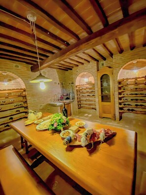 Ein Essbereich mit einem Holztisch, gedeckt für eine Mahlzeit, einem Weinregal und einer Pendelleuchte.