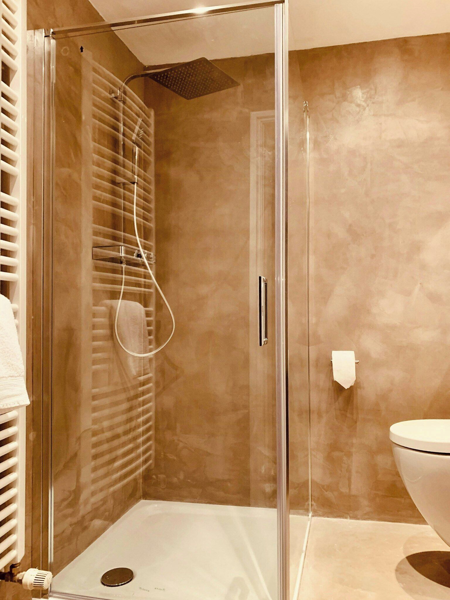 Une salle de bain moderne avec une douche à parois de verre, des toilettes et un porte-serviettes.