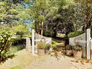 Ein Weg schlängelt sich durch einen Garten mit weißen Zäunen und Blumentöpfen.