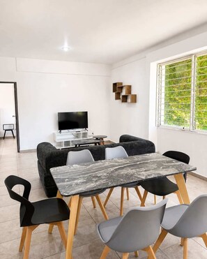 Un salon moderne avec un téléviseur, un canapé, une table à manger et des chaises.