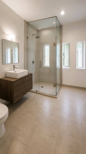 A modern bathroom with a glass-enclosed shower, a vanity with a sink, and a toilet. - Departamento privado, Milan Providencia (Guadalajara)