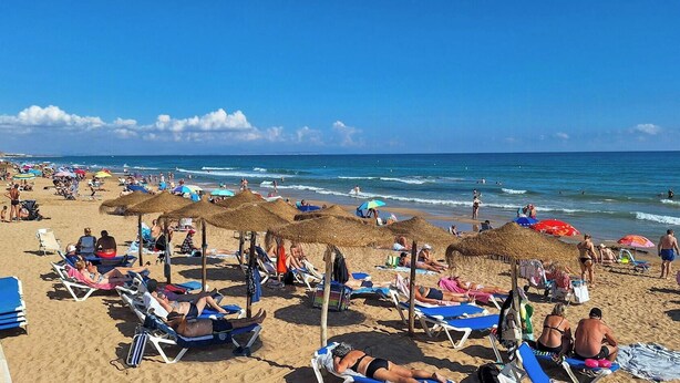 A beach with sun loungers, umbrellas, and people enjoying the seaside. - Ibizan design villa in Costa Blanca with pool (Torrevieja)