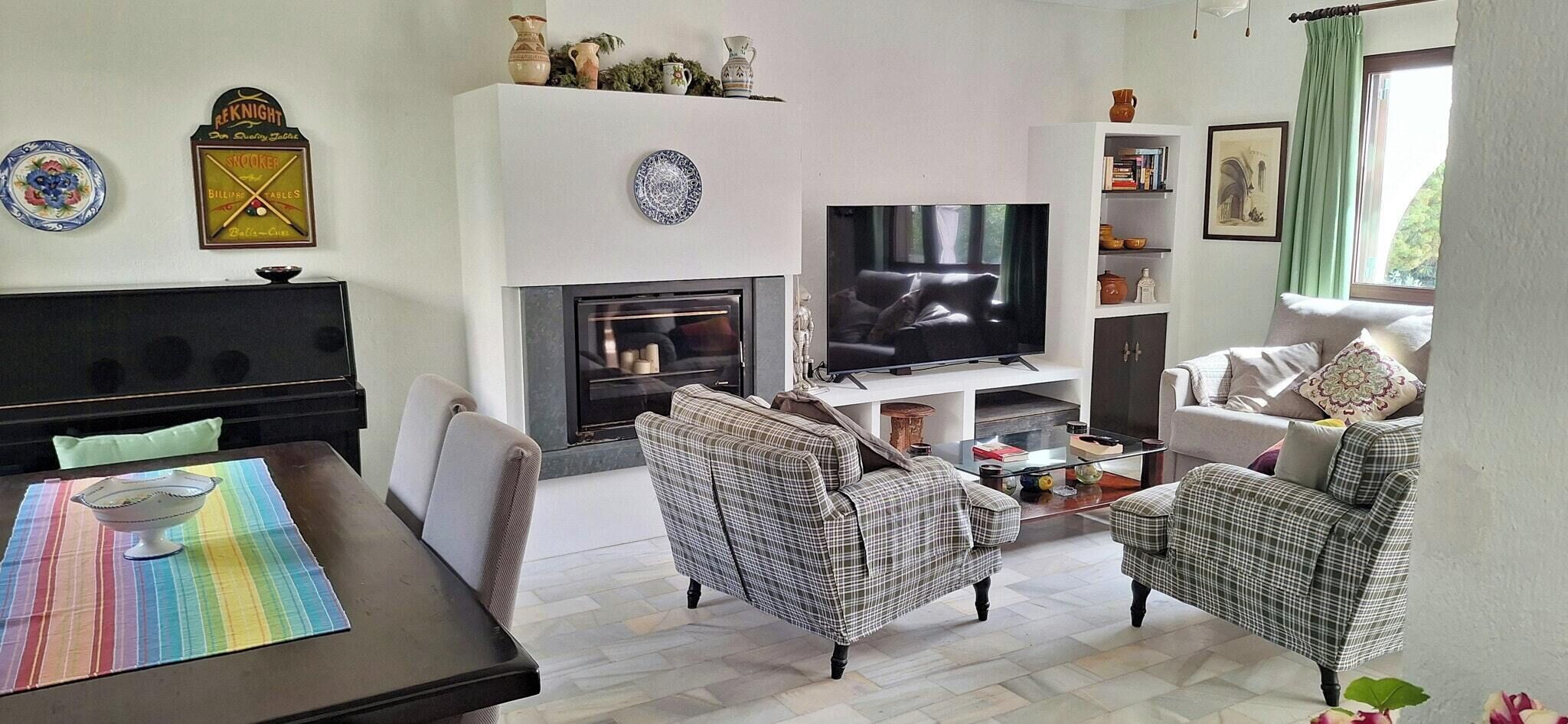 Un salón con chimenea, televisi ón y zona de estar.