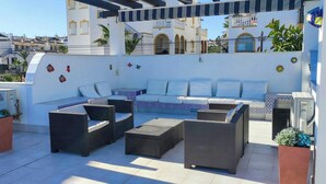 A rooftop patio with a sofa set, two side tables, and potted plants. - Ibizan design villa in Costa Blanca with pool (Torrevieja)