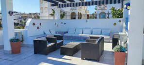Eine Dachterrasse mit einer Sofagarnitur, zwei Beistelltischen und Topfpflanzen.