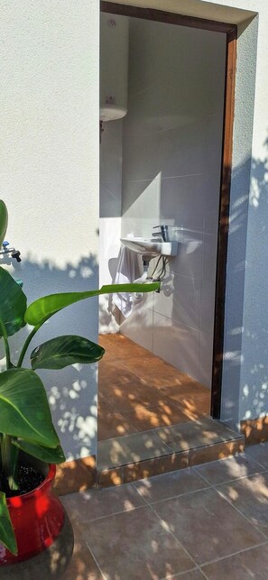 Ein Badezimmer mit einem weißen Waschbecken, einem Handtuch auf einem Wäscheständer und einer Topfpflanze im Vordergrund.