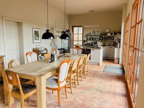 Ein Essbereich mit einem langen Holztisch, mehreren Stühlen und Pendelleuchten.