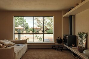 Ein Zimmer mit großem Fenster, einer Couch, einem Fernseher und einem kleinen Tisch.