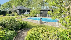 A backyard with a swimming pool, a small shed, and a house with a dark roof. - Relax in the countryside with pool (Aulum)