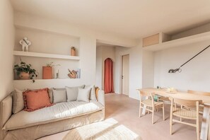 A modern living space with a sofa, dining table, and chairs, a shelf with decorative items, and a door leading to another room. - Mediterranean retreat with sea view in Seborga (Seborga)