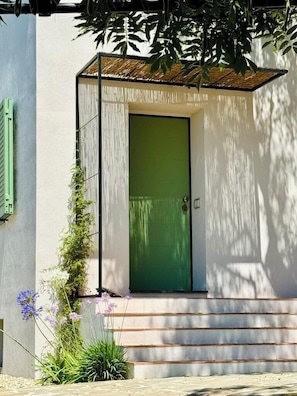 A modern building with a green door, a small porch, and steps leading up to the entrance. - Mediterranean retreat with sea view in Seborga (Seborga)