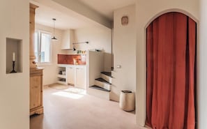 A hallway leading to a kitchen with a red curtain, a wooden cabinet, and a tiled backsplash. - Mediterranean retreat with sea view in Seborga (Seborga)