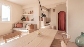 Ein zeitgemäßer Wohnraum mit einem Holzespeiseplatz, einer Couch mit Kissen, einer Treppe und einem roten Vorhang.
