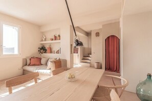 A modern living space with a wooden dining table, a sofa with cushions, a staircase, and a red curtain. - Mediterranean retreat with sea view in Seborga (Seborga)
