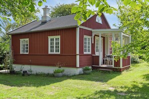 A red house with a porch, white trim, and a chimney. - The small, red wooden house with lots of charm (Vejby Strand)