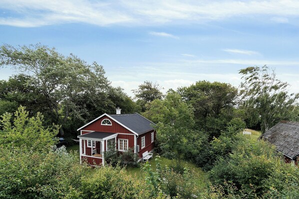 A red house surrounded by dense greenery. - The small, red wooden house with lots of charm (Vejby Strand)