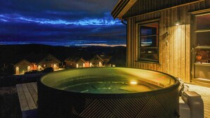 Un jacuzzi frente a un edificio de madera con vistas al paisaje.