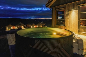 Ein Whirlpool vor einem Holzbau mit Blick auf die Landschaft.
