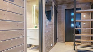 Un interior de madera con un baño, un espejo y un banco de madera.