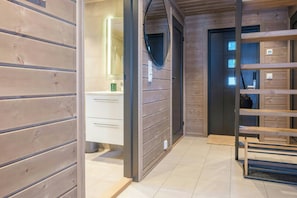 Ein Holzinnenraum mit Badezimmer, Spiegel und einer hölzernen Bank.