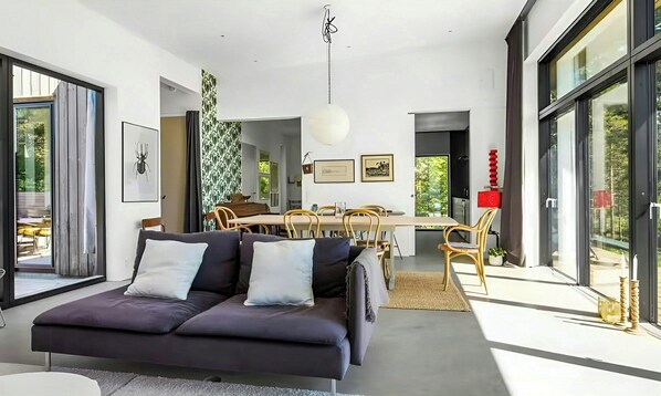 A modern living room with a sofa, dining table, and chairs.