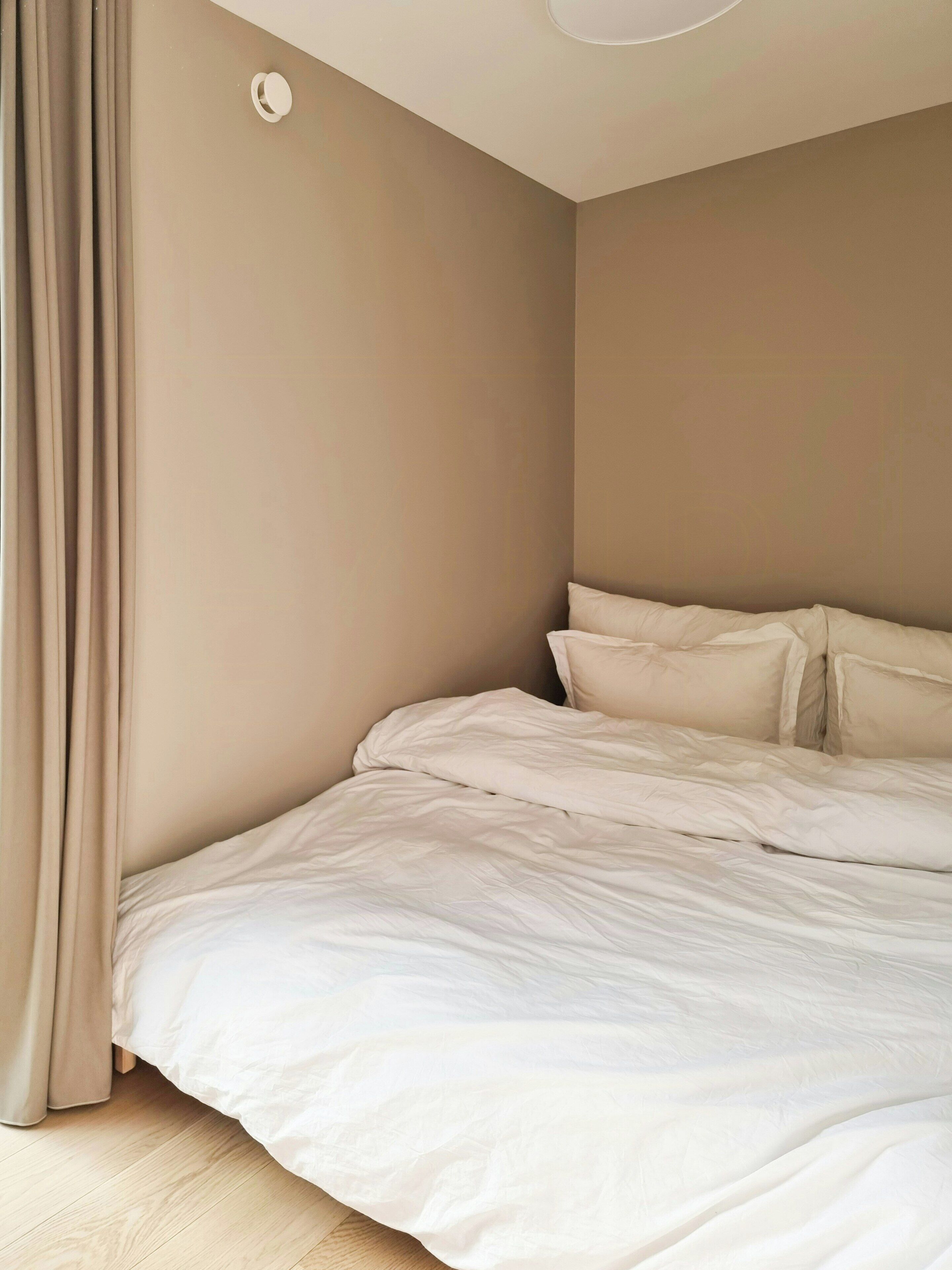 A bedroom with a bed, curtains, and a ceiling light fixture.